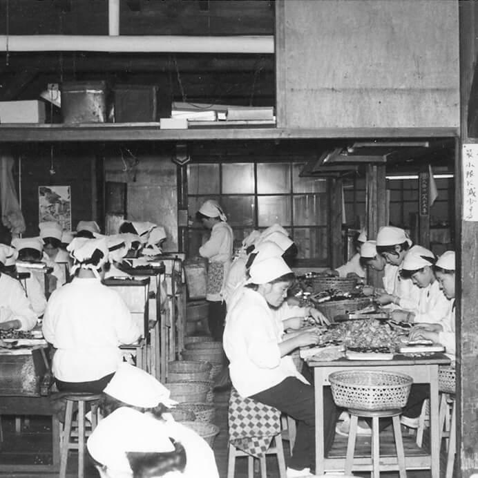 写真：福光町新町の自家工場にて。当時は1本ずつ海苔を手巻きしていた。（1939年（昭和14年）ごろ）
